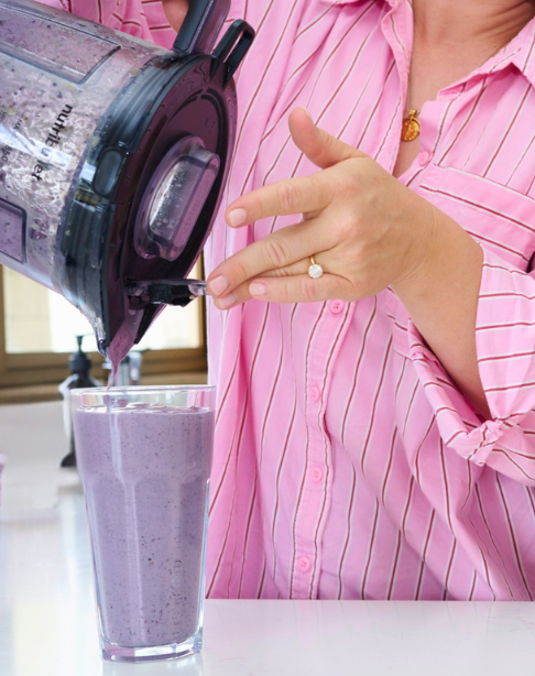 Person pouring a purple smoothie from a blender into a glass.